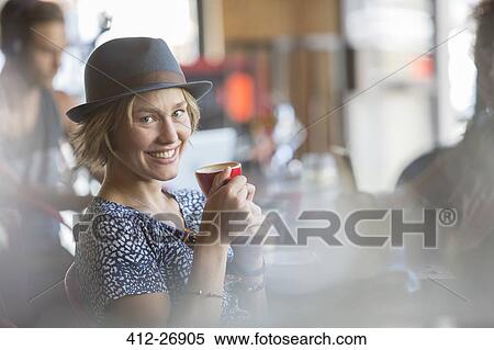 Stock Photography - Portrait smiling woman in hat drinking espresso in cafe. Fotosearch