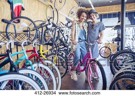 Portrait smiling women hugging with bicycle in bicycle shop View Large Photo Image Picture - Portrait smiling women hugging with bicycle in bicycle shop. Fotosearch