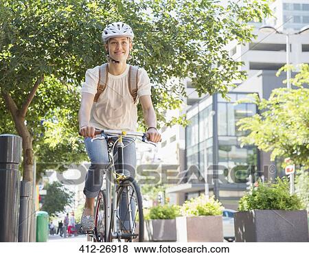 Portrait smiling young woman in helmet riding bicycle in urban park View Large Photo Image Stock Photo - Portrait smiling young woman in helmet riding bicycle in urban park. Fotosearch