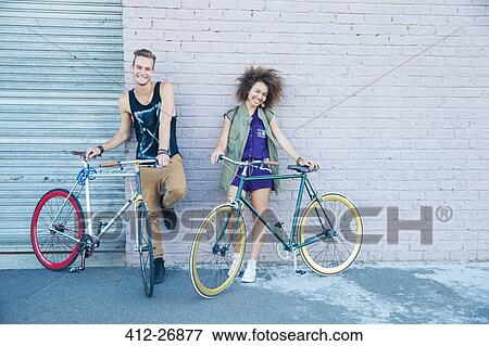 Portrait young man and young woman with bicycles at urban wall View Large Photo Image Stock Photo - Portrait young man and young woman with bicycles at urban wall. Fotosearch