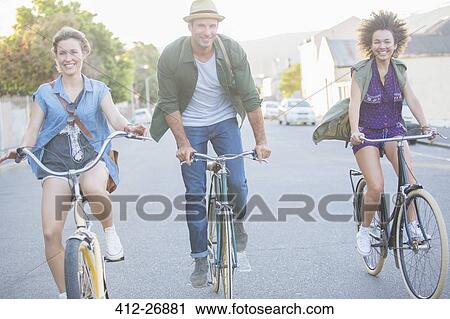 Smiling friends riding bicycles on street View Large Photo Image Stock Image - Smiling friends riding bicycles on street. Fotosearch