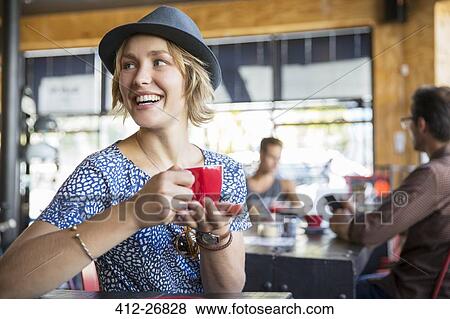 Smiling woman drinking coffee looking over shoulder in cafe View Large Photo Image Stock Photo - Smiling woman drinking coffee looking over shoulder in cafe. Fotosearch