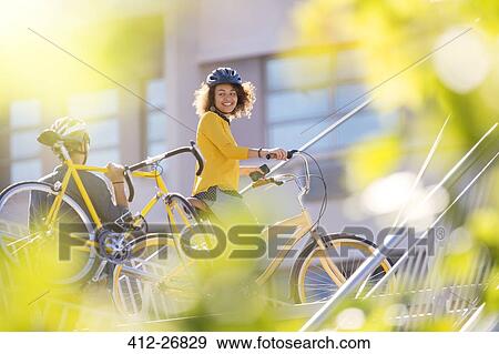 Stock Photo - Smiling woman with bicycle in city. Fotosearch