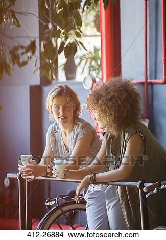Women drinking on coffee leaning on railing in bicycle shop View Large Photo Image Picture - Women drinking on coffee leaning on railing in bicycle shop. Fotosearch