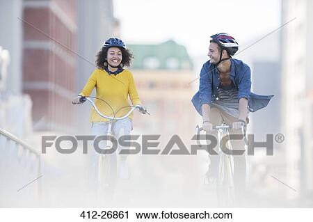 Young couple riding bicycles in city View Large Photo Image Stock Image - Young couple riding bicycles in city. Fotosearch