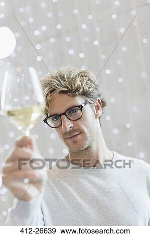 Stock Photo - Close up man examining white wine. Fotosearch