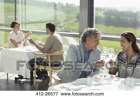 Stock Photo - Couple toasting wine glasses in sunny winery dining room. Fotosearch