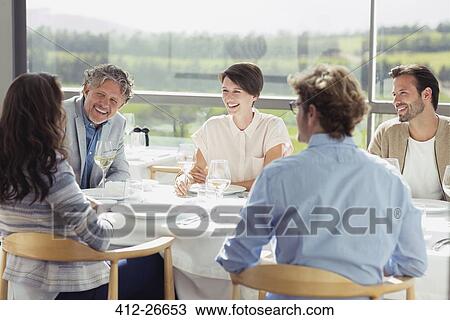 Friends drinking white wine and talking at sunny restaurant table View Large Photo Image Stock Image - Friends drinking white wine and talking at sunny restaurant table. Fotosearch