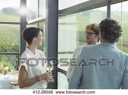 Stock Photograph - Friends drinking white wine in winery tasting room. Fotosearch