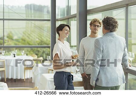 Friends talking and drinking wine in winery dining room View Large Photo Image Stock Photograph - Friends talking and drinking wine in winery dining room. Fotosearch