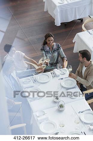 Friends toasting wine glasses at restaurant table View Large Photo Image Stock Photo - Friends toasting wine glasses at restaurant table. Fotosearch