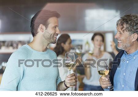 Stock Photography - Friends wine tasting and talking in winery tasting room. Fotosearch