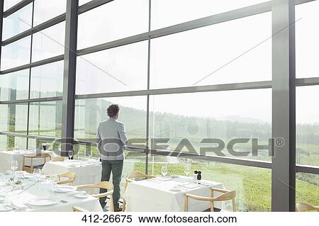 Man standing at sunny window in winery dining room View Large Photo Image Stock Photography - Man standing at sunny window in winery dining room. Fotosearch