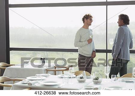 Stock Photo - Men drinking wine at restaurant window. Fotosearch