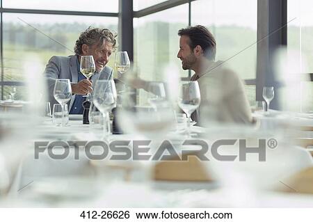 Men toasting wine glasses at restaurant table View Large Photo Image Stock Photograph - Men toasting wine glasses at restaurant table. Fotosearch