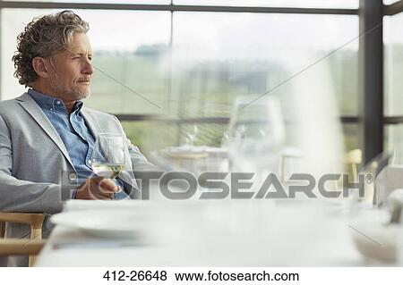 Pensive man drinking white wine in winery dining room View Large Photo Image Stock Photo - Pensive man drinking white wine in winery dining room. Fotosearch