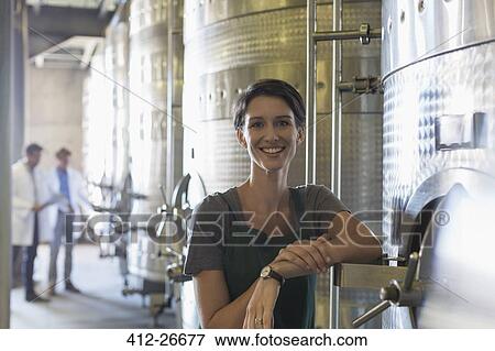 Stock Photo - Portrait smiling vintner at stainless steel vat in winery cellar. Fotosearch