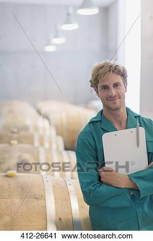 Portrait smiling vintner with clipboard in winery cellar View Large Photo Image Stock Image - Portrait smiling vintner with clipboard in winery cellar. Fotosearch