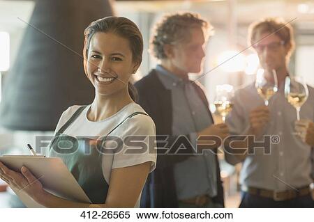 Stock Photography - Portrait smiling woman with clipboard working in wine tasting room. Fotosearch