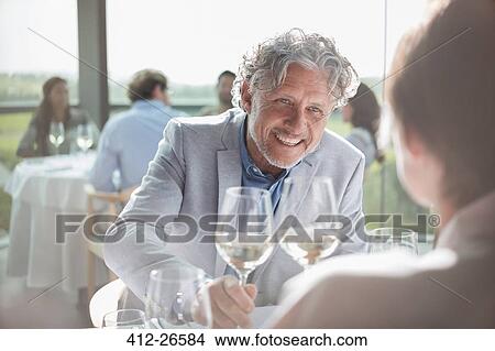 Smiling couple drinking wine in sunny restaurant View Large Photo Image Picture - Smiling couple drinking wine in sunny restaurant. Fotosearch