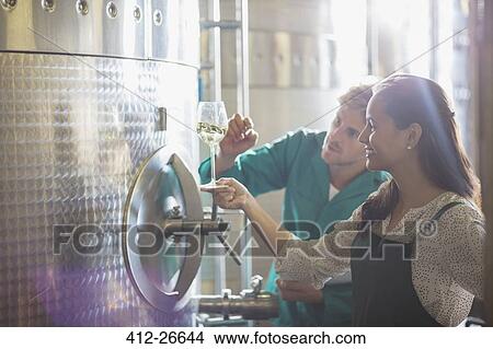 Vintners examining white wine at stainless steel vat in winery cellar View Large Photo Image Picture - Vintners examining white wine at stainless steel vat in winery cellar. Fotosearch