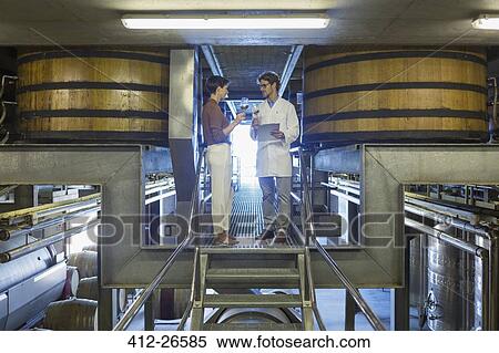 Stock Photography - Vintners examining wine on platform in winery cellar. Fotosearch