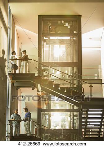 Vintners standing on platforms in sunny winery View Large Photo Image Stock Photo - Vintners standing on platforms in sunny winery. Fotosearch