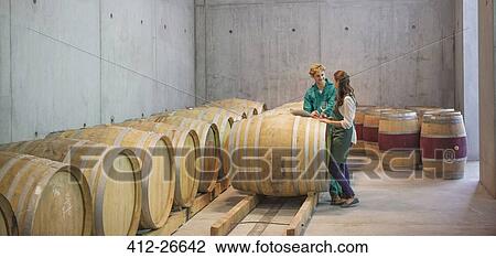 Vintners talking at barrels in winery cellar View Large Photo Image Stock Image - Vintners talking at barrels in winery cellar. Fotosearch