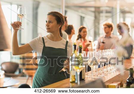 Stock Photo - Wine tasting room worker examining white wine. Fotosearch