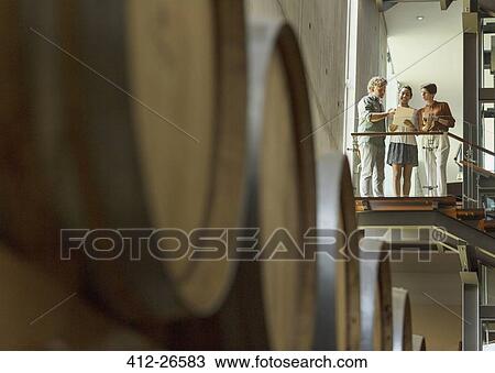 Stock Image - Winery employees talking on platform in cellar. Fotosearch