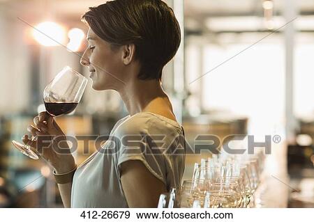 Stock Photo - Woman wine tasting red wine in winery tasting room. Fotosearch