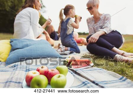 Apples and watermelon on picnic blanket near multi-generation family View Large Photo Image Stock Image - Apples and watermelon on picnic blanket near multi-generation family. Fotosearch