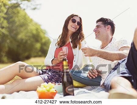Couple drinking champagne on picnic blanket in sunny field View Large Photo Image Stock Photo - Couple drinking champagne on picnic blanket in sunny field. Fotosearch