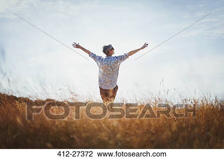 Exuberant senior woman with arms outstretched in sunny field View Large Photo Image Stock Image - Exuberant senior woman with arms outstretched in sunny field. Fotosearch