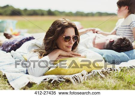 Stock Photography - Family relaxing on blanket in sunny field. Fotosearch