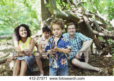 Family watching boy play with sticks in woods View Large Photo Image Stock Image - Family watching boy play with sticks in woods. Fotosearch