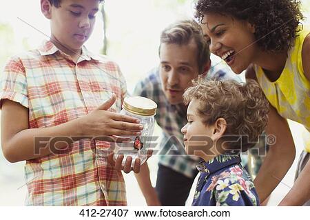 Stock Photo - Family watching butterfly in jar. Fotosearch