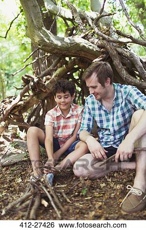 Father and son making small campfire with sticks in woods View Large Photo Image Stock Photograph - Father and son making small campfire with sticks in woods. Fotosearch