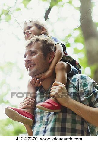 Stock Image - Father carrying son on shoulders. Fotosearch