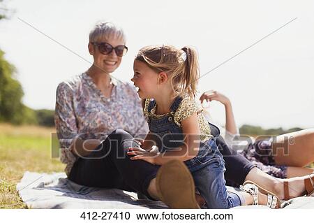 Grandmother and granddaughter laughing on blanket in sunny field View Large Photo Image Stock Image - Grandmother and granddaughter laughing on blanket in sunny field. Fotosearch