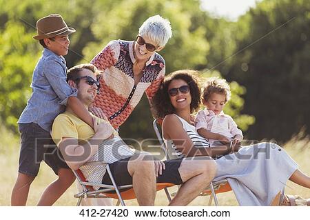 Multi-generation family relaxing in sunny field View Large Photo Image Stock Image - Multi-generation family relaxing in sunny field. Fotosearch