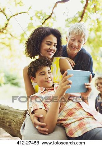 Stock Photo - Multi-generation family using digital tablet outdoors. Fotosearch