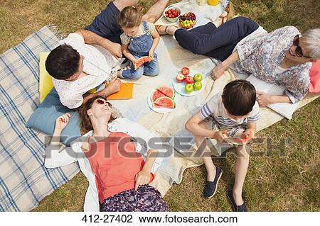 Stock Image - Overhead view multi-generation family enjoying summer picnic. Fotosearch