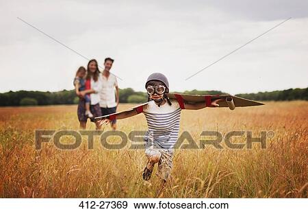 Playful boy with wings in aviator’s cap and flying goggles in field View Large Photo Image Stock Photo - Playful boy with wings in aviator’s cap and flying goggles in field. Fotosearch