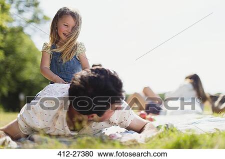 Playful daughter on top of father in sunny field View Large Photo Image Stock Image - Playful daughter on top of father in sunny field. Fotosearch