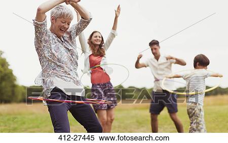 Stock Photography - Playful multi-generation family spinning in plastic hoops in field. Fotosearch