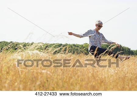 Playful senior woman dancing in sunny rural field View Large Photo Image Stock Image - Playful senior woman dancing in sunny rural field. Fotosearch