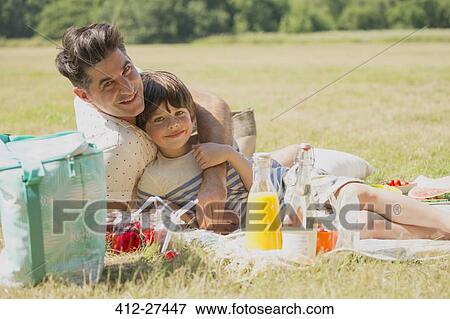 Portrait affectionate father and son relaxing on picnic blanket in sunny field View Large Photo Image Stock Photo - Portrait affectionate father and son relaxing on picnic blanket in sunny field. Fotosearch
