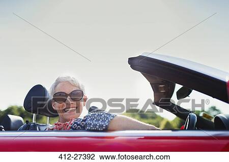 Stock Image - Portrait senior woman driving convertible. Fotosearch