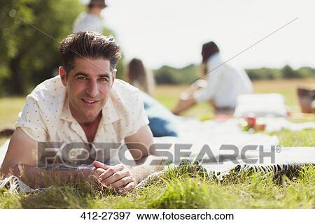 Portrait smiling man laying on picnic blanket in sunny field View Large Photo Image Stock Photo - Portrait smiling man laying on picnic blanket in sunny field. Fotosearch